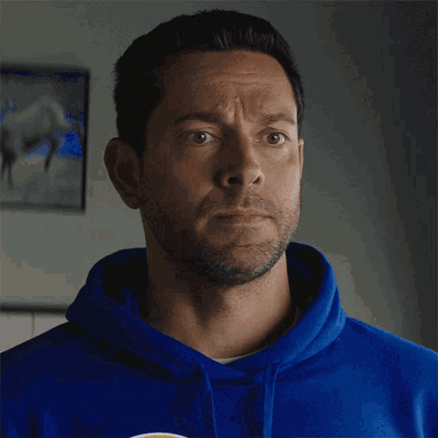 a man wearing a blue hoodie with a yellow and white stripe on it