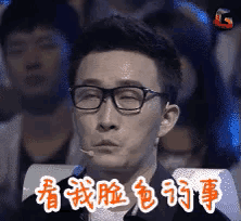 a man wearing glasses is sitting in front of a microphone with chinese writing on it