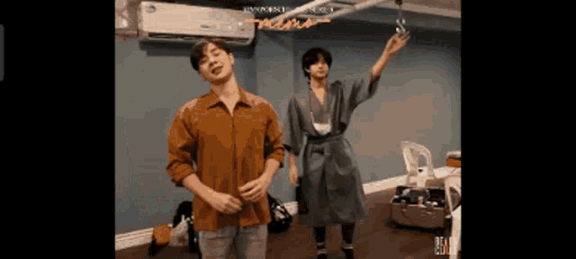 a couple of men are dancing in a room and one of them is wearing a bathrobe .
