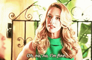 a woman in a green dress is standing in front of a wrought iron gate and talking .