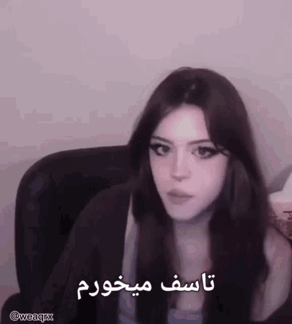 a girl is sitting in a chair with a foreign language written on her face