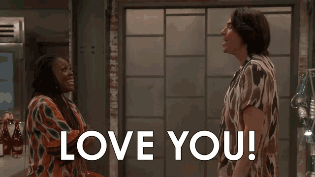 a man and a woman are standing next to each other with the words love you written on the screen