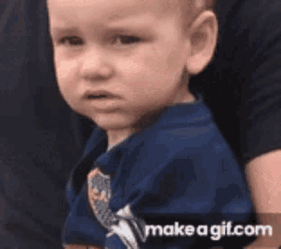 a baby in a blue shirt is being held by a person .