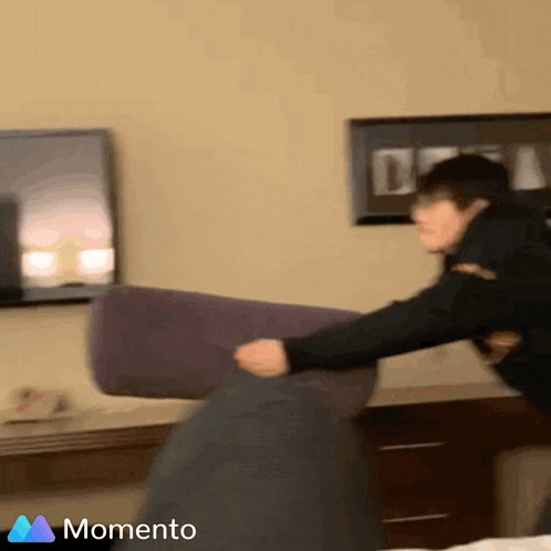 a man throws a pillow in a room with a momento logo