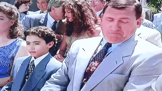 a man in a suit and tie is standing next to a boy in a blue suit and tie .