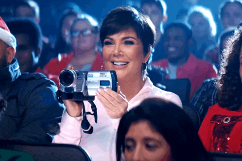 a woman is holding a camcorder that says ' nikon ' on the front
