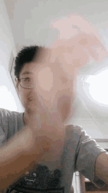 a man wearing glasses and a t-shirt with a bear on it throws something