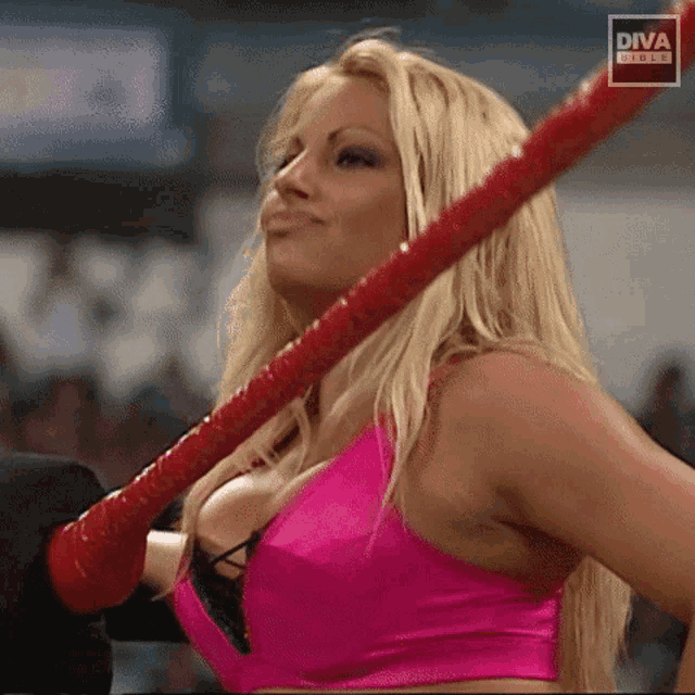 a blonde woman in a pink top is holding a red rope with diva written on the bottom
