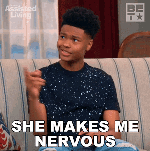 a young man sitting on a couch with the words she makes me nervous behind him
