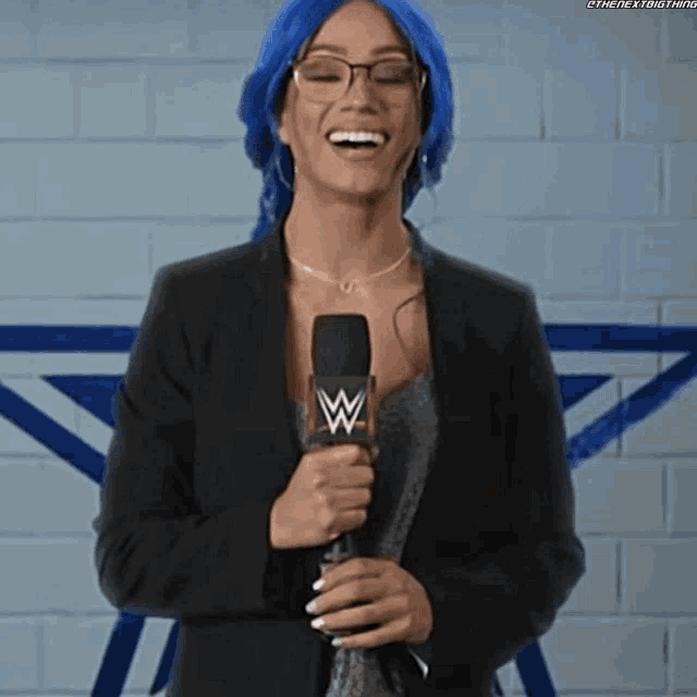 a woman with blue hair and glasses is holding a microphone .