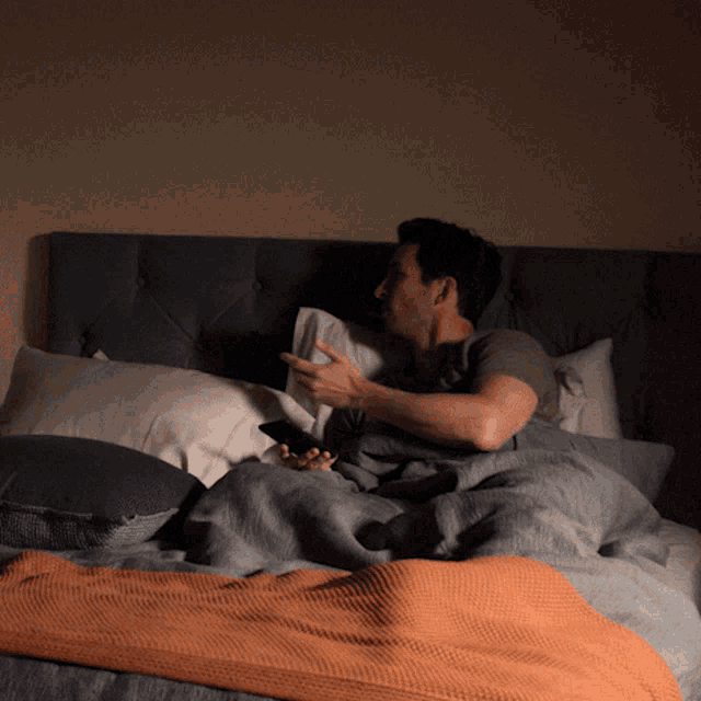 a man is laying on a bed with a phone in his hand
