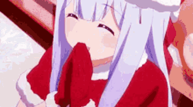 a girl with white hair is wearing a santa claus costume and holding a red object in her hand .