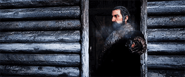 a man with a beard is smoking a cigarette in a log cabin