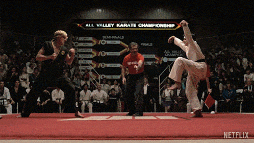 two karate fighters are fighting in front of an all valley karate championship sign