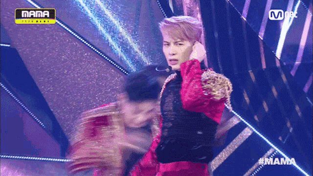 a man in a red outfit is standing on a stage in front of a mama logo