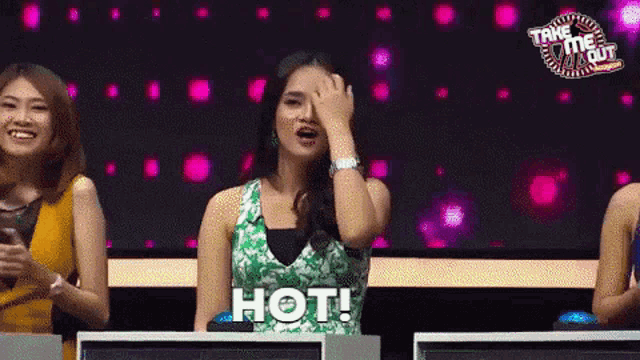 a woman covering her face with her hand while sitting in front of a screen that says hot