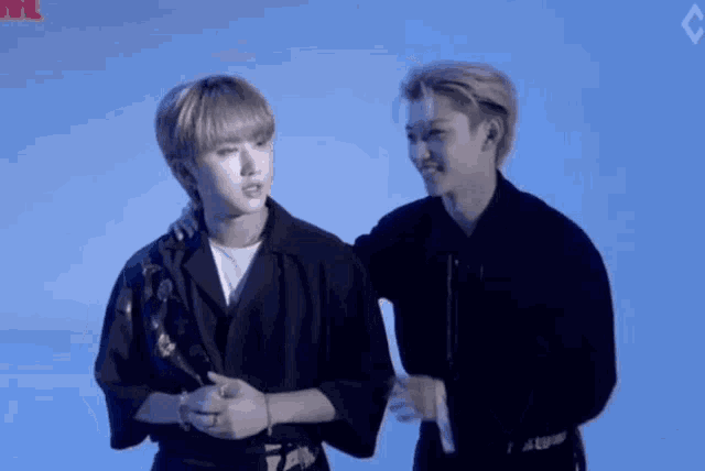 two young men are standing next to each other and one of them is holding the other 's arm .