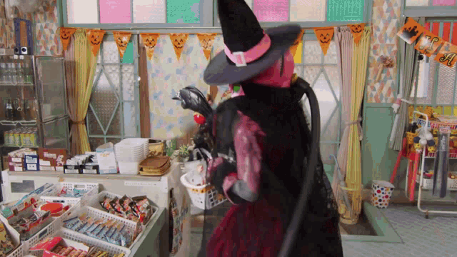 a woman in a witch costume is standing in front of a display of candy