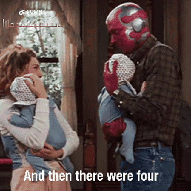 a man in a red mask is holding a baby in his arms while a woman looks on ..