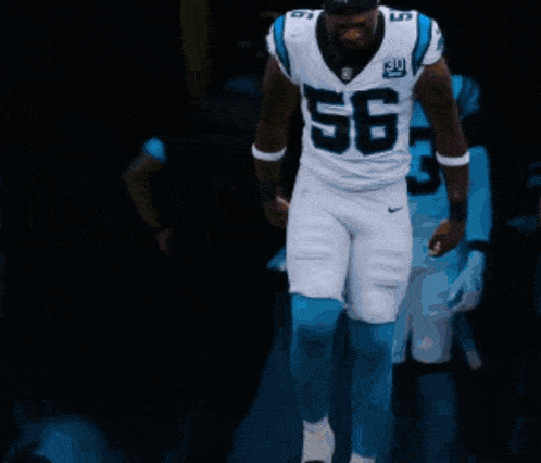 a football player with the number 56 on his jersey walks with his teammates