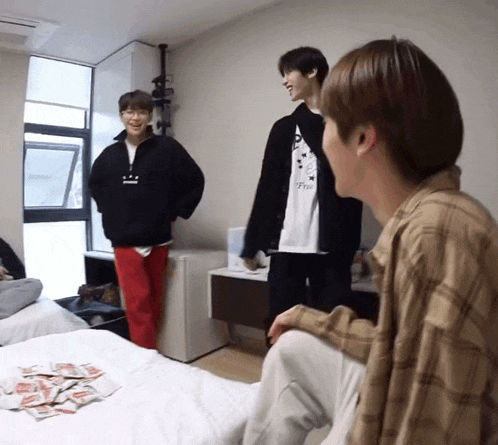 a man in a plaid shirt is sitting on a bed next to another man
