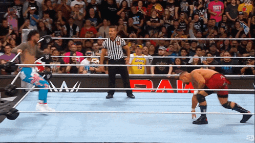a wrestler wearing a lakers jersey stands in the ring