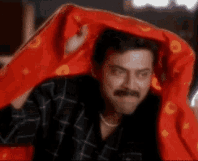 a man is wrapped in a red blanket over his head .