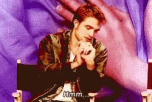 a man sits in a chair with his hands folded and says " hmm "