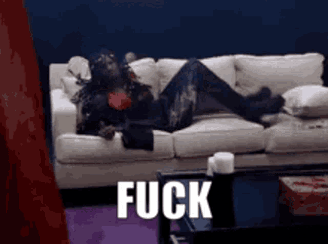 a person is laying on a couch with the word fuck written on it