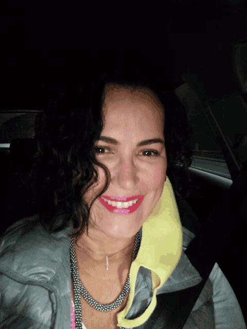 a woman in a car with a yellow towel around her neck smiles