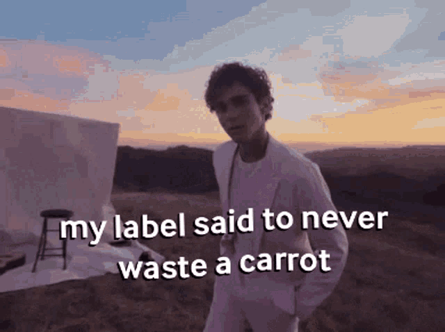 a man in a white suit is standing in a field with the words " my label said to never waste a carrot "