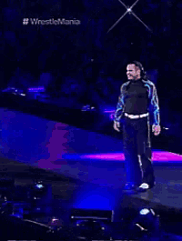 a man is dancing on a stage in front of a sign that says # wrestlemania