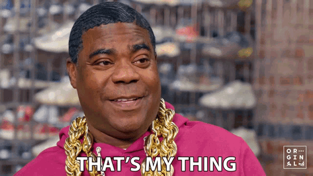 a man wearing a pink hoodie and gold chains says that 's my thing