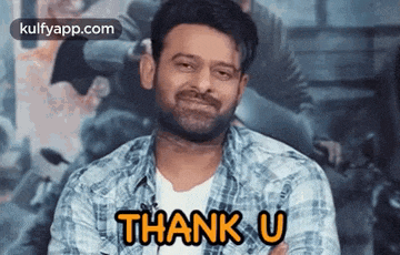 a man in a plaid shirt is smiling and saying `` thank you '' .