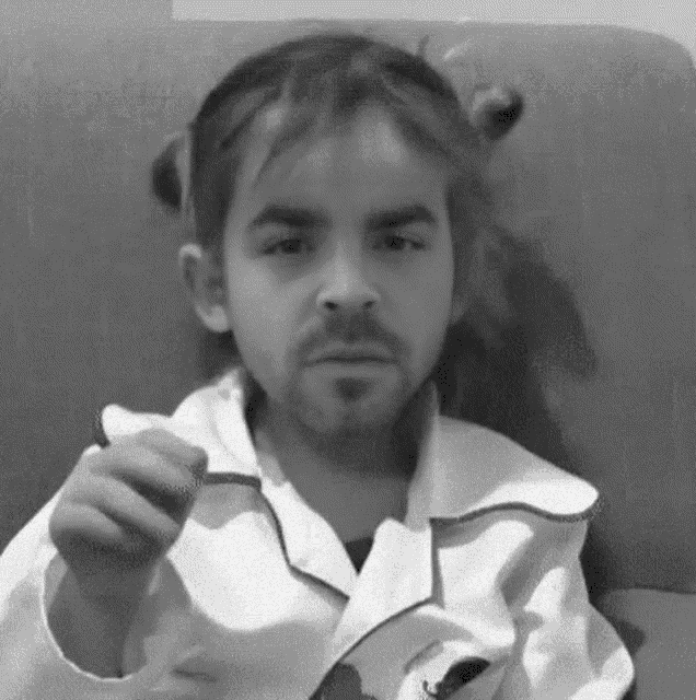 a little girl with a beard is sitting on a couch eating a piece of food .