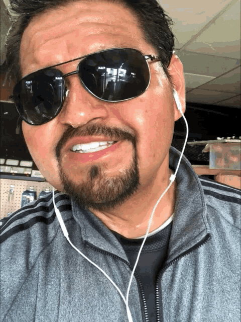 a man with a beard wearing sunglasses and earbuds