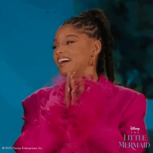 a woman in a pink jacket is applauding while wearing a ponytail .