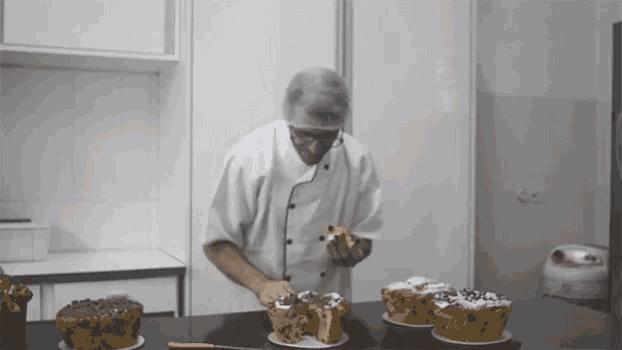 a man in a white chef 's coat is eating a piece of cake