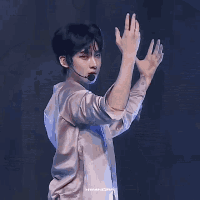 a man wearing a satin shirt and a microphone is dancing on a stage