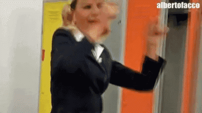 a woman in a suit is standing in front of a locker and making a face .
