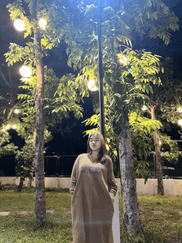 a woman wearing a dress that says abercrombie is standing in a park at night