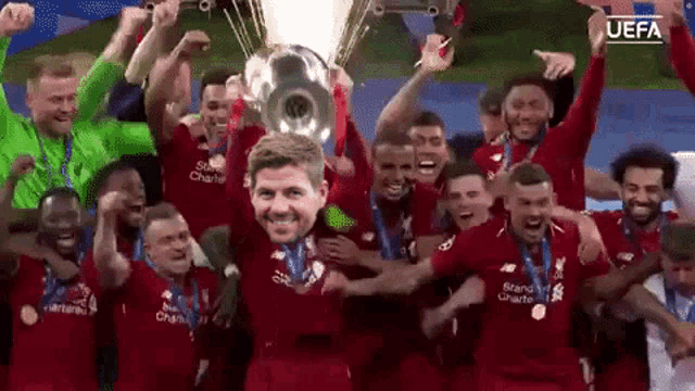 a group of soccer players holding up a trophy with a man 's face on it