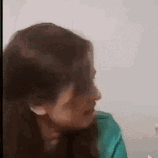 a close up of a woman 's face with long hair and a green shirt .