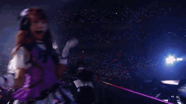 a woman with red hair in a purple dress is dancing on a stage