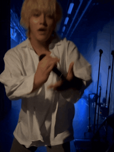 a man in a white shirt is holding a microphone and dancing