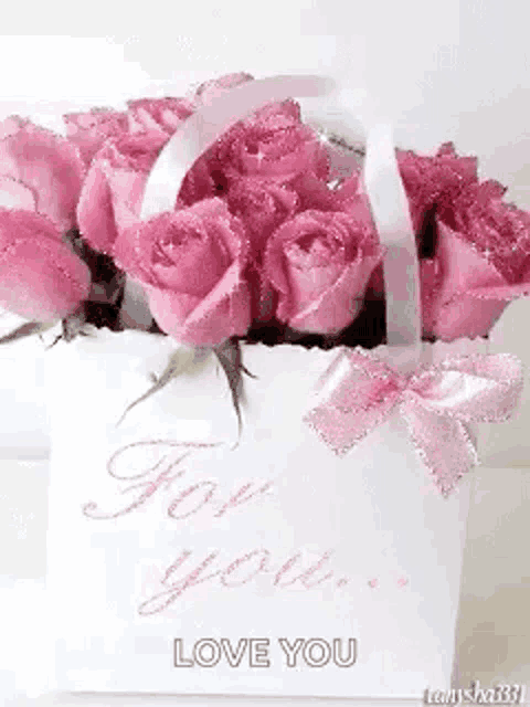 a white bag filled with pink roses with a pink bow on it .