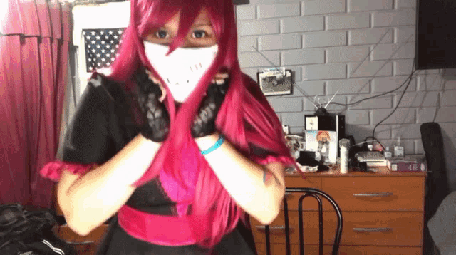a woman with pink hair wearing a white mask and gloves