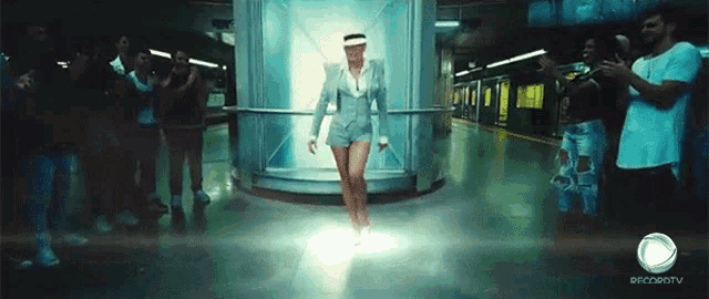 a woman in a suit and shorts is dancing in front of a crowd of people and a sign that says ofcsrotv