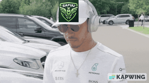 a man wearing headphones and a safuu hat stands in a parking lot