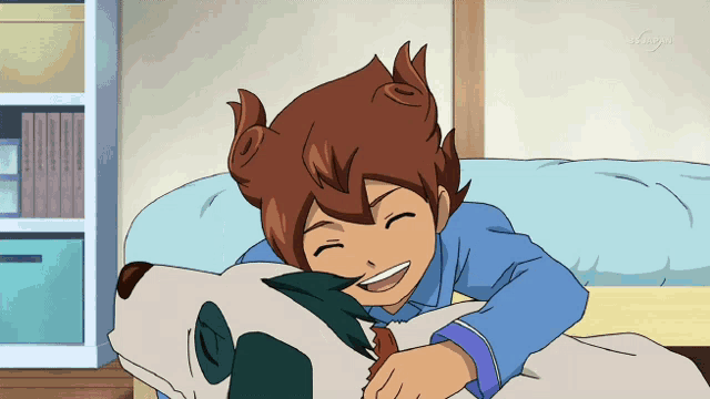 a boy is laying on a bed with a dog and smiling with tokyo on the bottom left